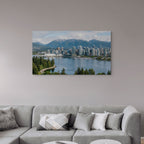 Cityscape with mountains and water on a wall above a gray sofa.