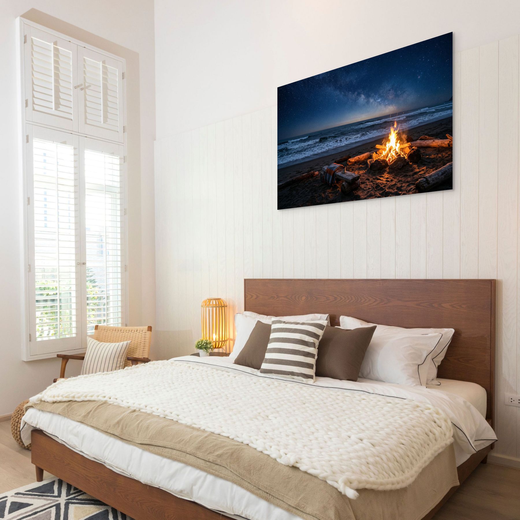 Bedroom with a large bed and a wall art of a beach scene with a fire.