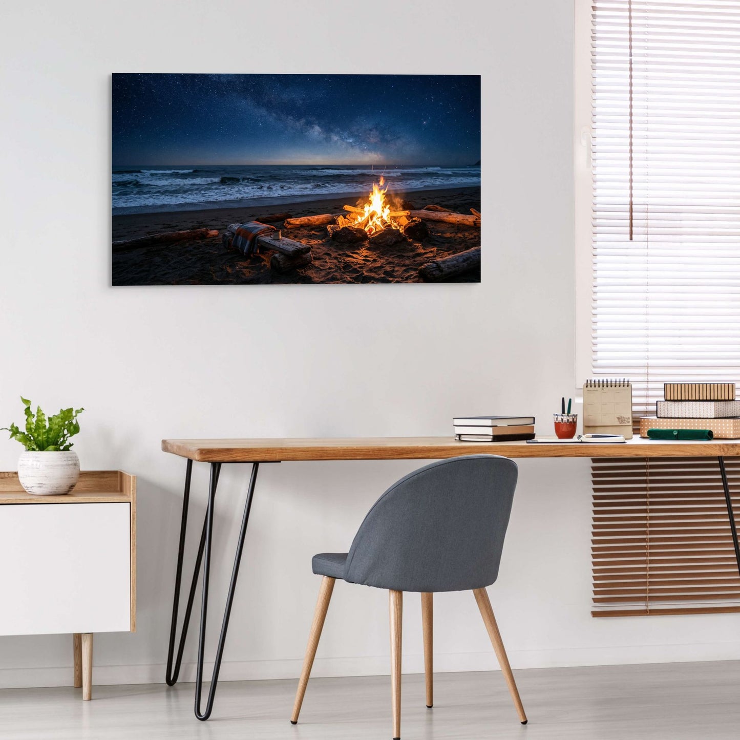 Beach scene with bonfire on wall above desk in home office.