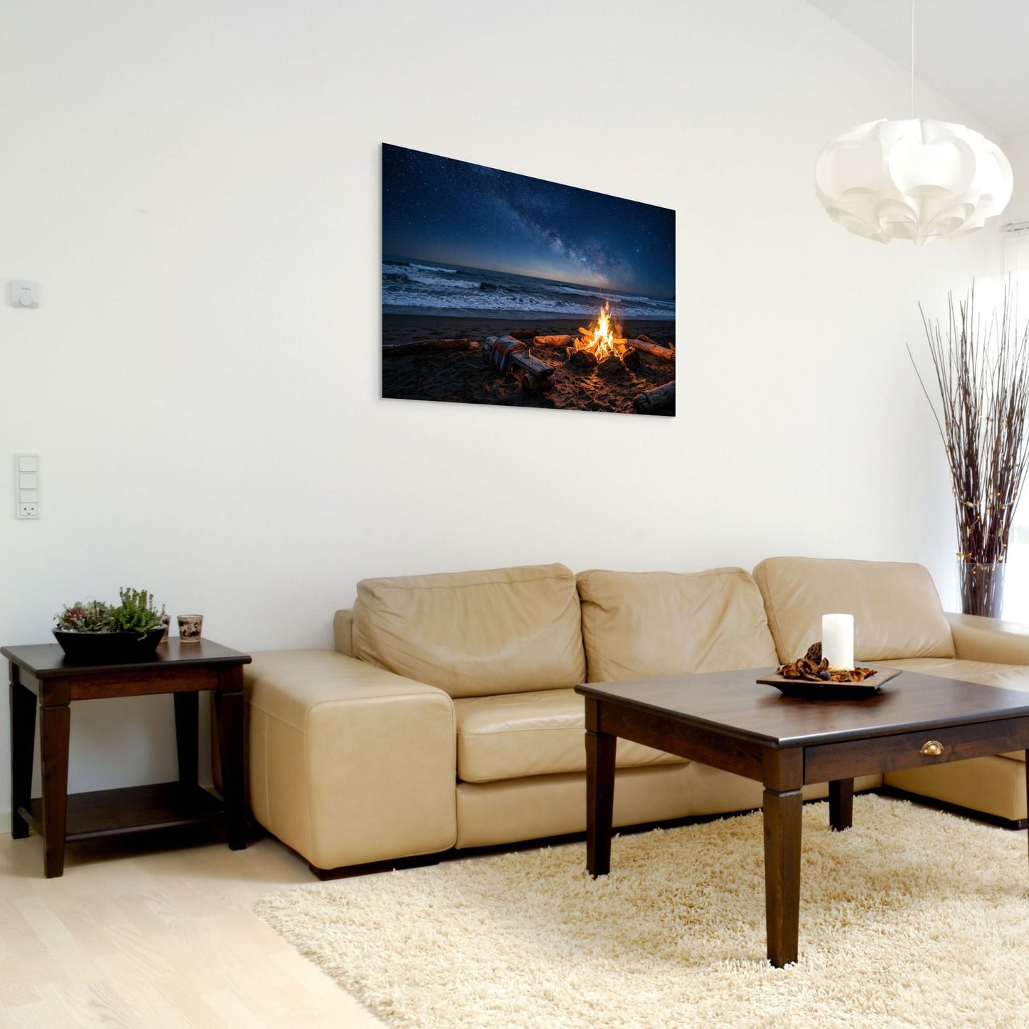 Living room with beige sofa, wooden coffee table, and wall art of a beach scene with fire.