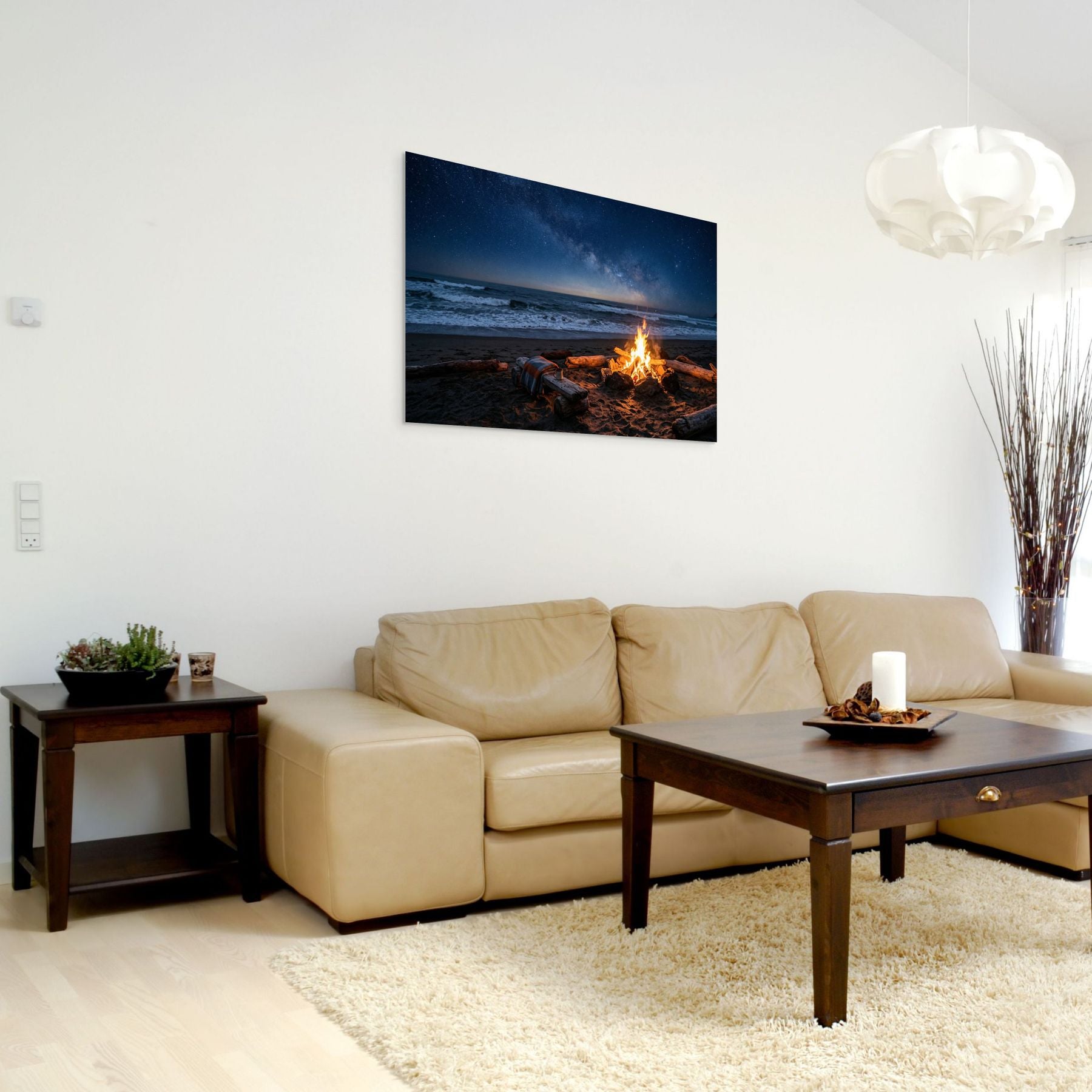 Living room with beige sofa, wooden coffee table, and wall art of a beach scene with fire.