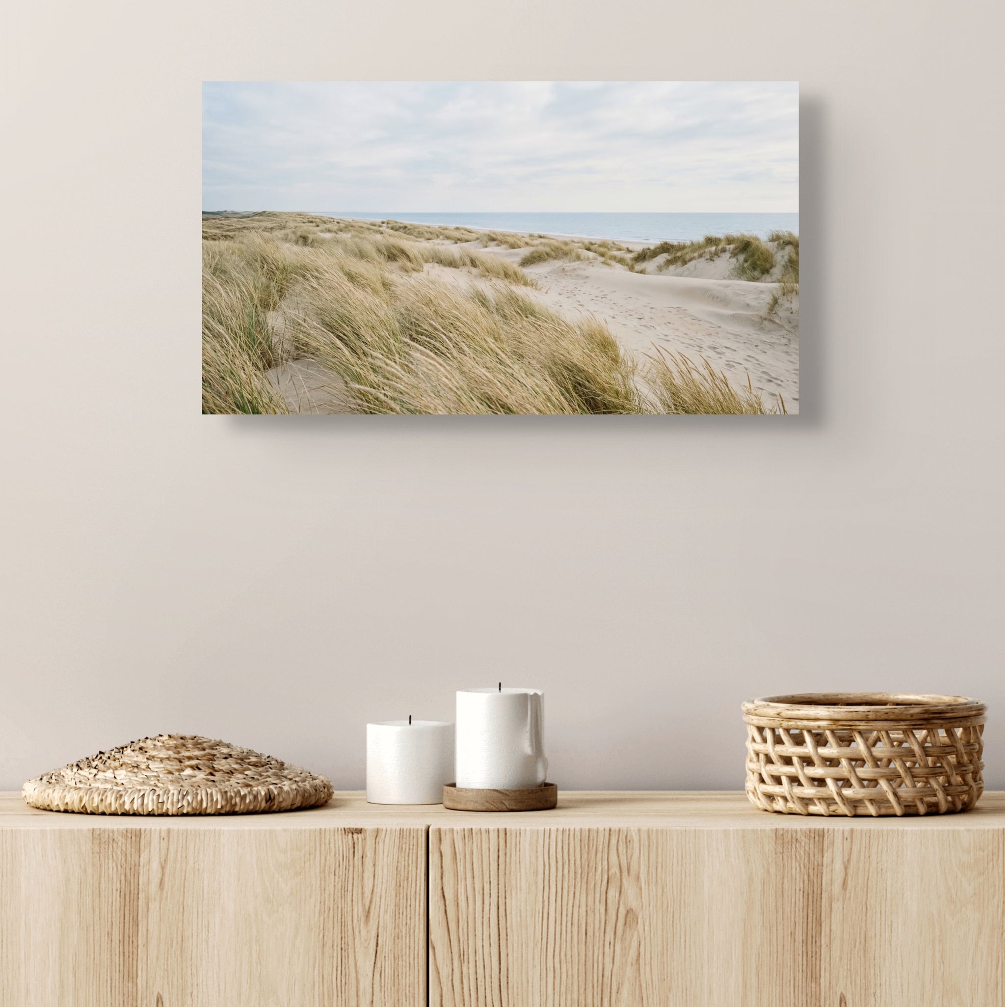Canvas print of a beach scene with sand dunes on a wall above a wooden shelf.