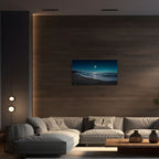 Modern living room with a large TV displaying a beach scene, gray sectional sofa, and wooden coffee table.
