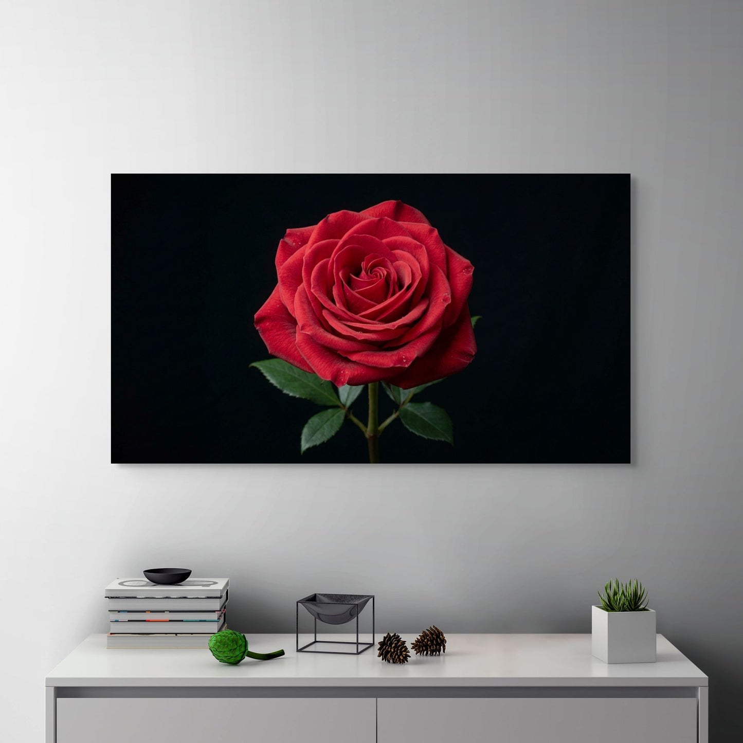 Large framed photograph of a red rose on a wall above a white cabinet with decorative items.