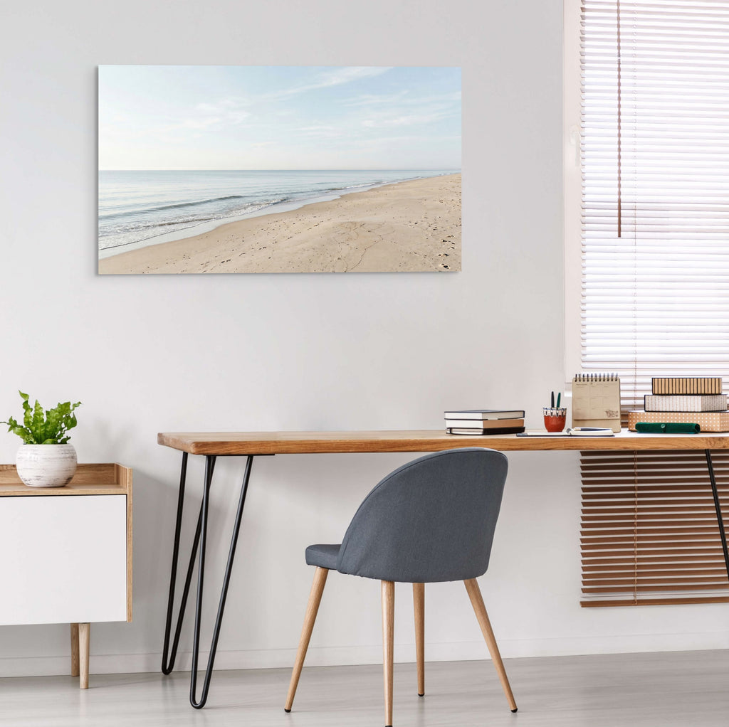 Modern home office with a desk, chair, and beach-themed wall art.