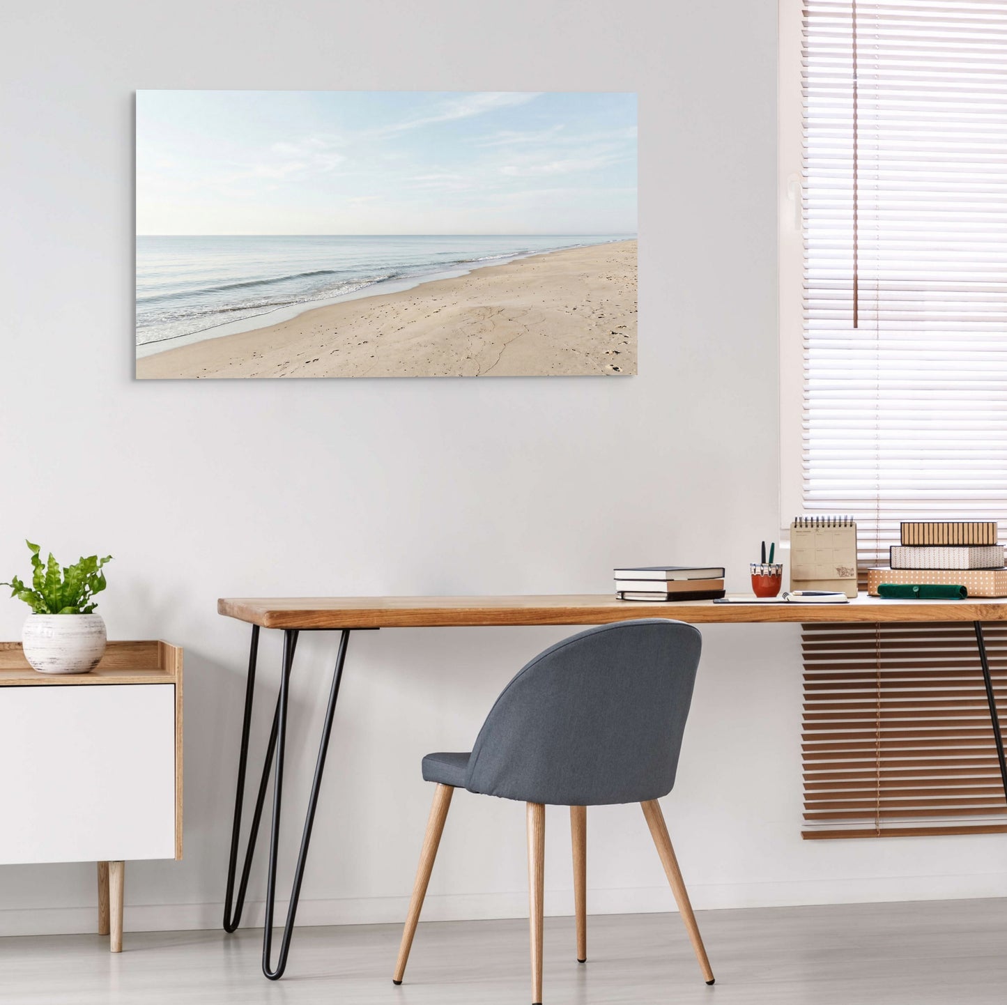 Modern home office with a desk, chair, and beach-themed wall art.
