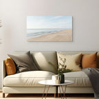 Beige sofa with decorative pillows and a small table in a living room, featuring a beach scene painting on the wall.