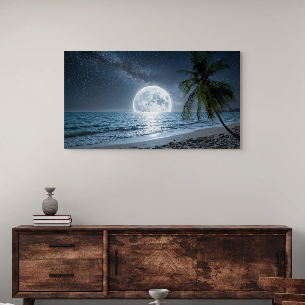 Framed artwork of a moonlit beach scene above a wooden console table.