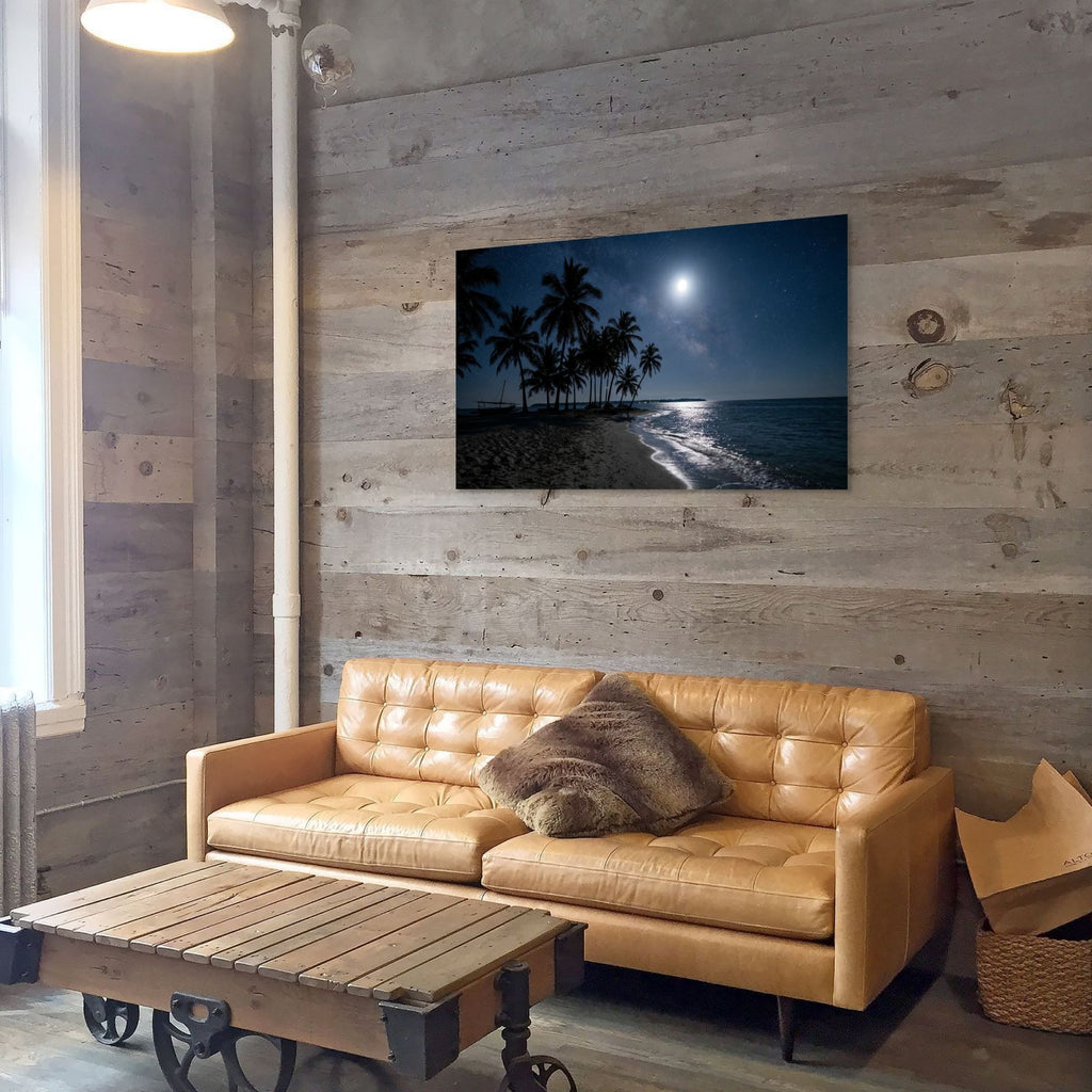 Tan leather sofa in a room with wooden walls and a beach scene painting.