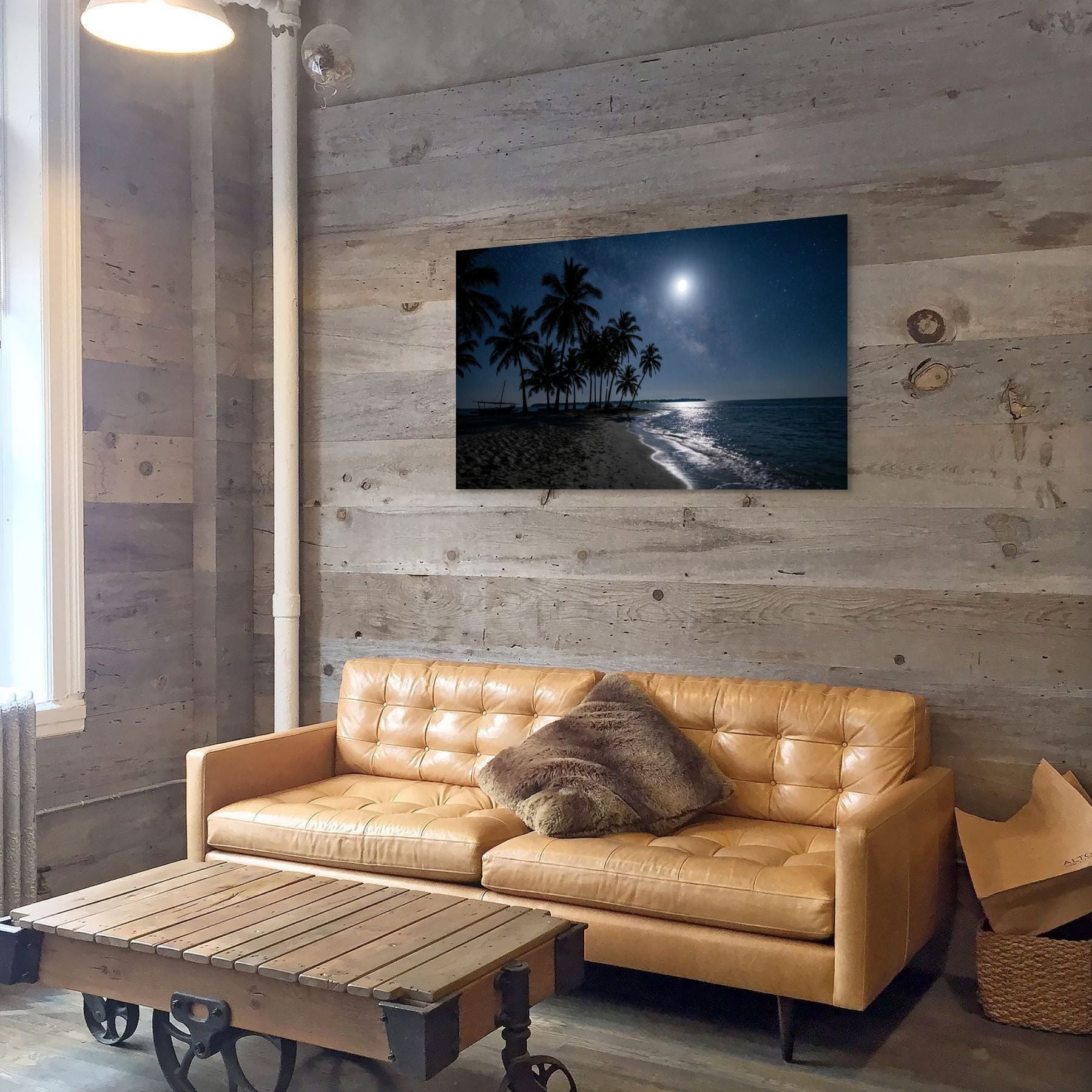 Tan leather sofa in a room with wooden walls and a beach scene painting.