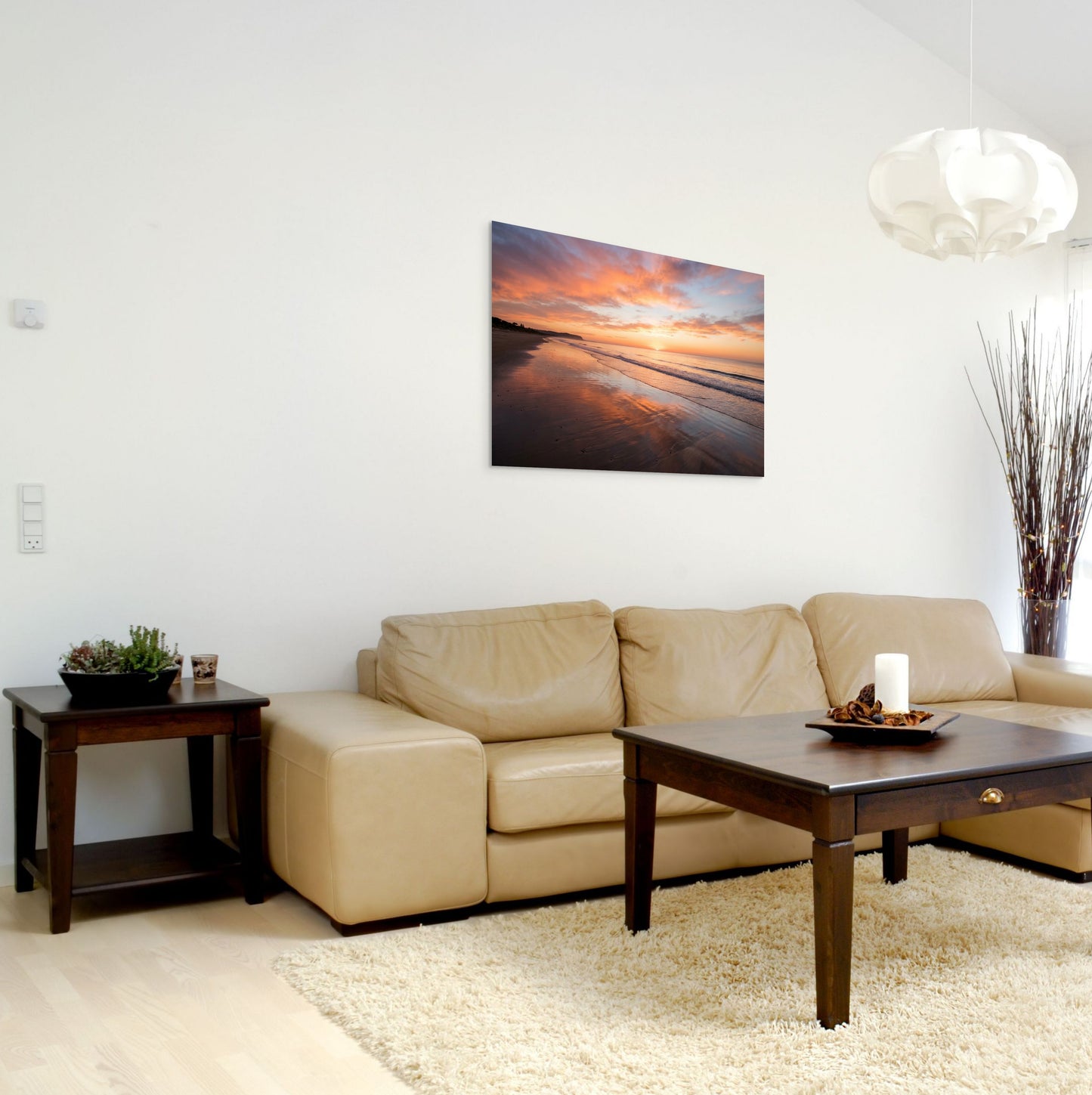 Modern living room with beige sofa, wooden coffee table, and beach scene artwork on wall.